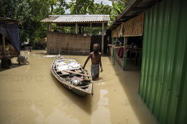Morigaon, India. 4 July 2024. A person dry his childrens books in a boat next to his flooded house