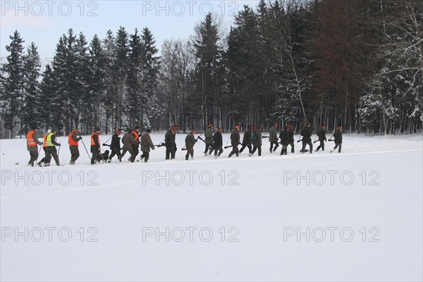 Hunters and hunting assistants, so-called beaters in the snow, on the way to the next drive, on the