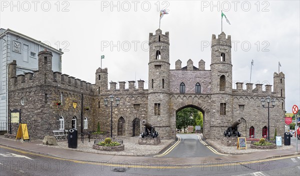 Imposing stone castle with flags and cannons, historical character on the street corner, Macroom