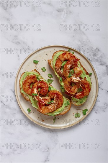 Sandwiches with avocado and caramelized shrimp, micro-greens, breakfast, on a plate, top view,