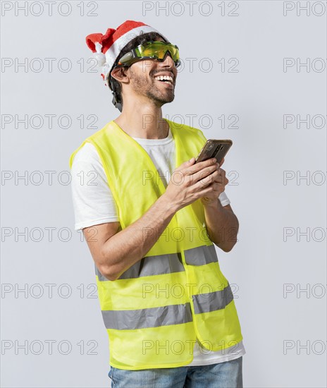 Happy Engineer in christmas hat using cell phone isolated. Smiling engineer in christmas hat using