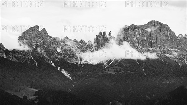 The peaks of the rose garden, shrouded in mist, drone shot, black and white image, Dolomites,