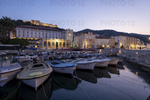 Illuminated harbour at sunrise with boats and historic buildings, Hvar, Croatia, Europe