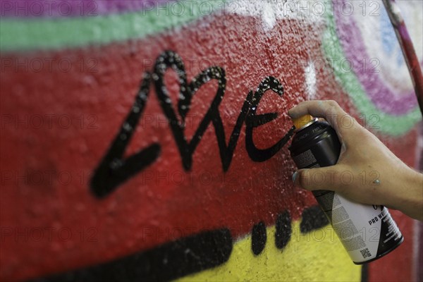A man sprays graffiti on a wall with a spray can. Berlin, 14.08.2024