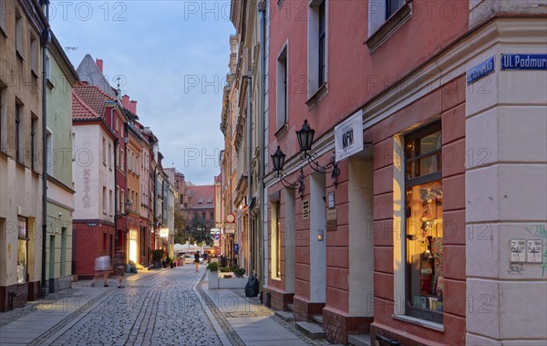 Shop windows illuminated in the evening on Szewska Street in the medieval Old Town of Thorn. The