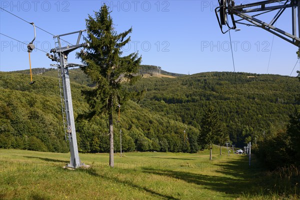 A cable car leads over a wooded hill under a clear blue sky in summer, Pezinska Baba ski resort,