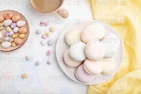 Colored zephyr or marshmallow with cup of coffee and dragees on white concrete background and