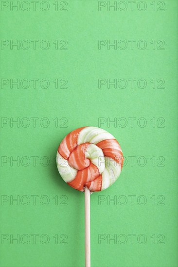 Single lollipop candy on green pastel background. copy space, top view, flat lay