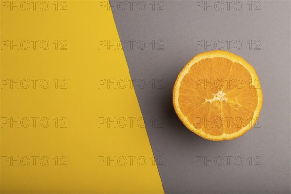 Ripe cut orange on gray and yellow pastel background. Top view, flat lay, copy space. Tropical,