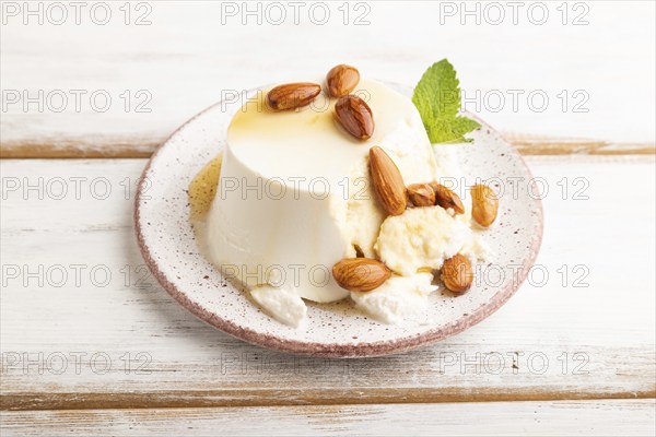 Ricotta cheese with honey and almonds on white wooden background. side view, close up