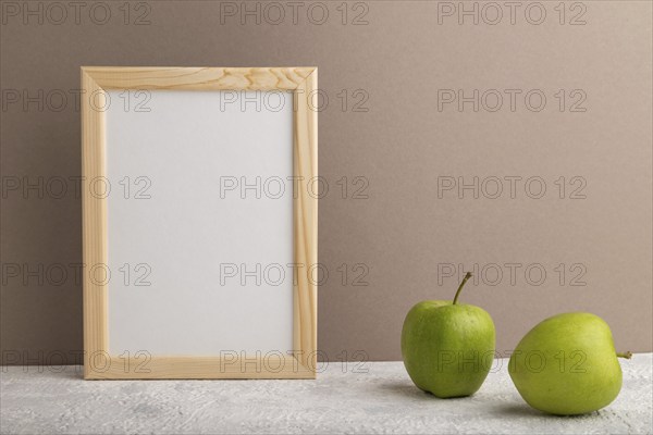 White wooden frame mockup with green apple on beige paper background. Blank, vertical orientation,