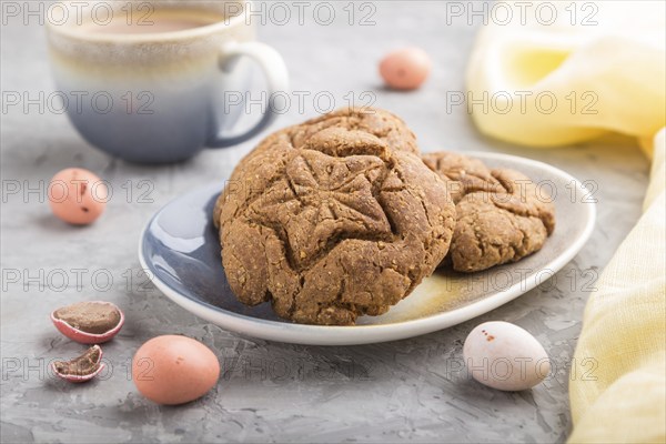 Homemade oatmeal cookies with a cup of cocoa and a yellow textile on a gray concrete background.