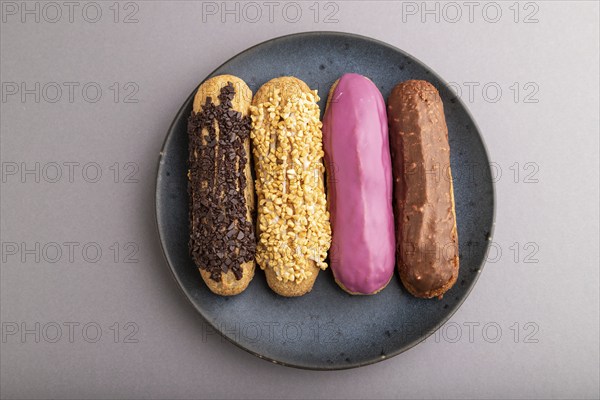 Set of eclair, traditional french dessert on blue ceramic plate on gray pastel background. top