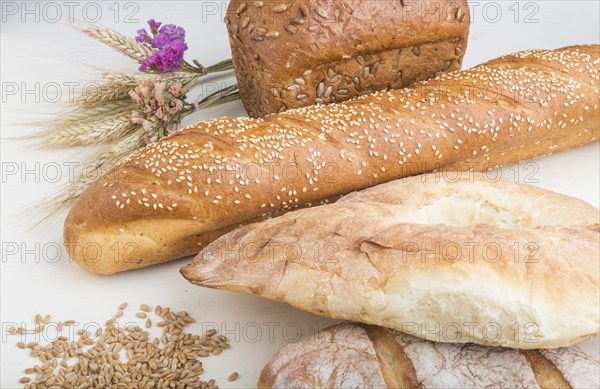 Different kinds of fresh baked bread on a white wooden background. side view, close up
