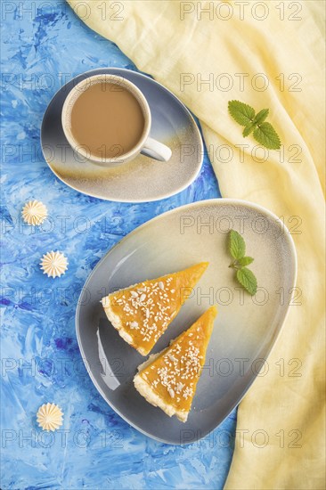 Two pieces of traditional american pumpkin pie with cup of coffee on a blue concrete background and