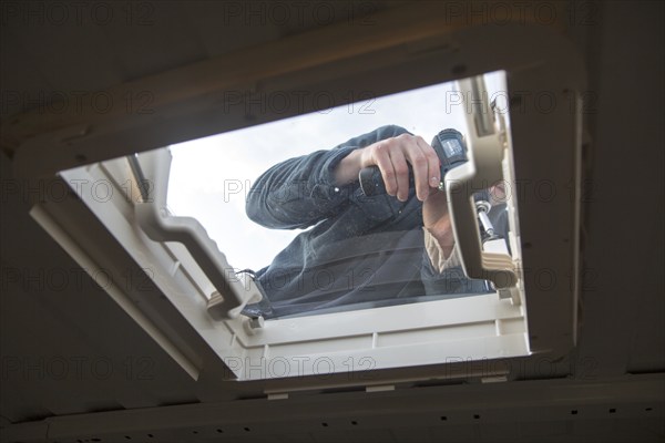 Cutting through roof of white metal camper van conversion to install ventilation window, UK