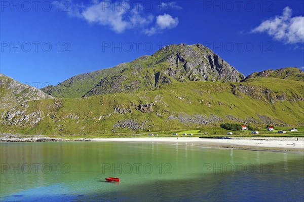 Crystal clear sandy beach with turquoise green water and a green boat, Haukland Strand, Leknes,