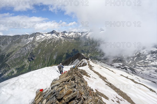Mountaineer on a rocky ridge with snow, descent from the summit of Schönbichler Horn, view of