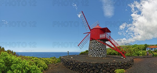 Red painted windmill on black volcanic stone Moinho de São João under a wide sky, São João, Pico