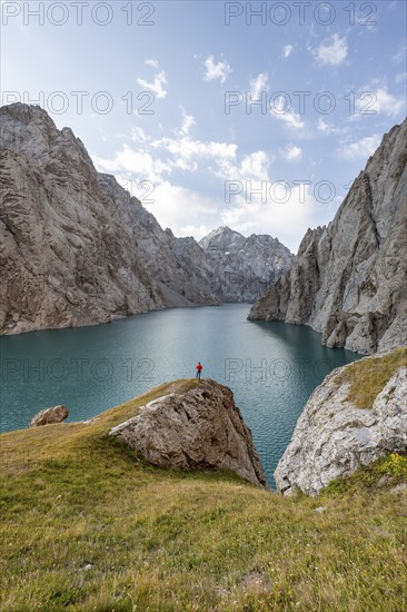 Tourist at the blue mountain lake between rocky steep mountain peaks, Kol Suu Lake, Sary Beles