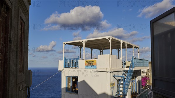 Veranda with panoramic sea view under a blue sky, with decorative railings, Colourful mountain