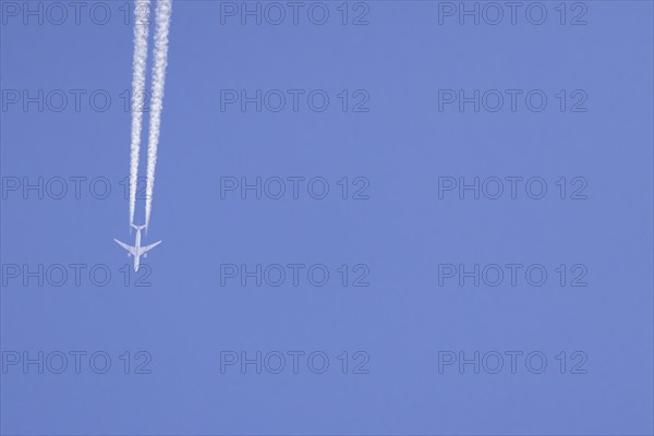 Airbus aircraft of Qatar airways flying across a blue sky with a vapour trail or contrail behind,