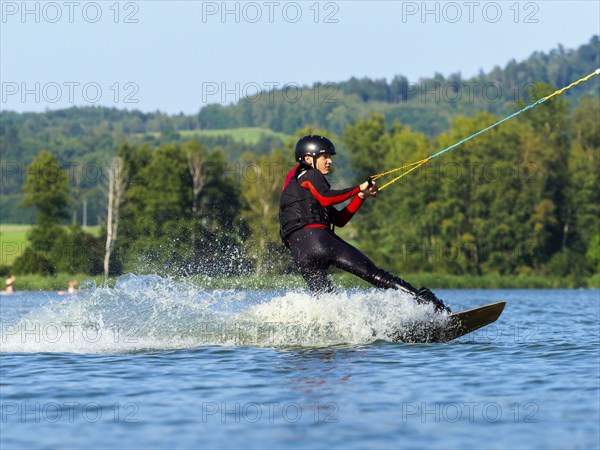 Young man doing sports with wakeboard in lake, water sports, water skiing in wakepark, Stráž pod