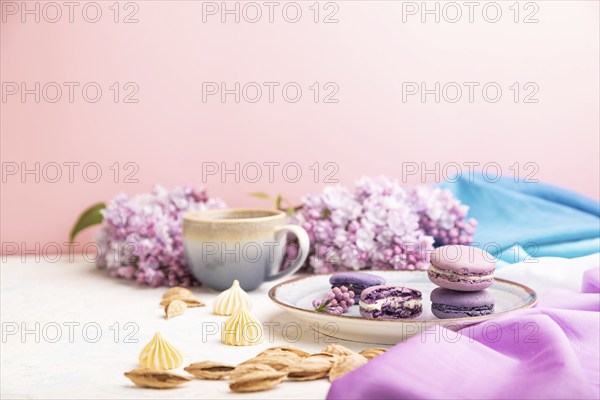 Purple macarons or macaroons cakes with cup of coffee on a white and pink background and