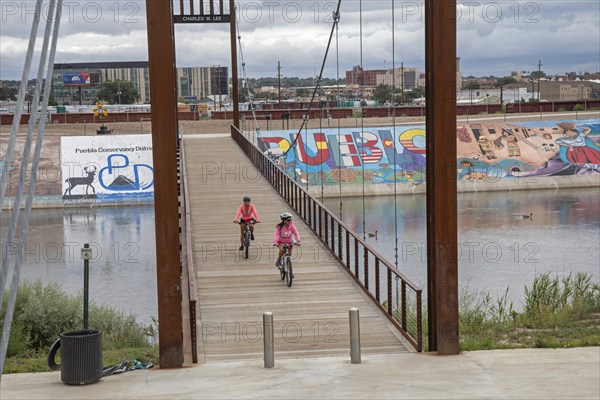 Pueblo, Colorado, Bicycle riders cross a bridge over the Arkansas River where murals and a bike