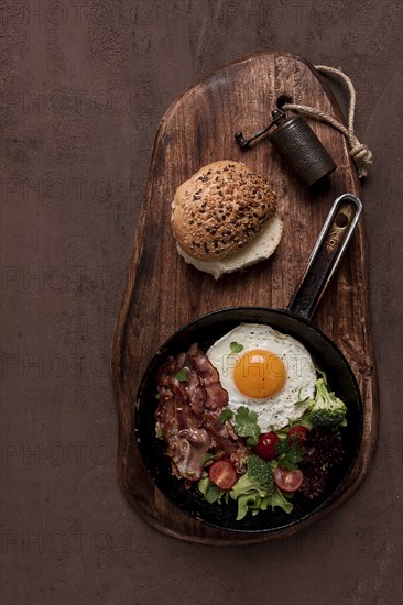 Fried egg, with bacon and vegetables, in a cast-iron frying pan, top view, homemade breakfast