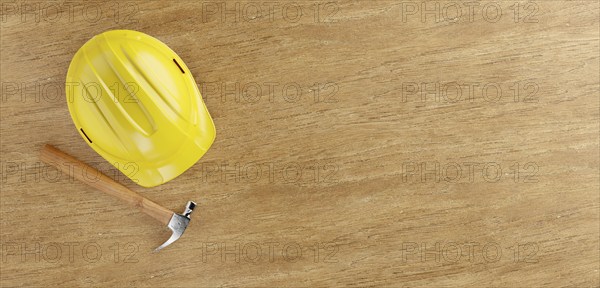 Overhead of yellow hard hat and hammer on a wood surface with room for text