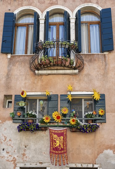 Windows decorated with flowers on a house facade, Venetian flag, Venice, Veneto, Italy, Europe
