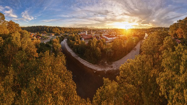 View of a town at sunset, surrounded by a river and autumnal trees under a dramatic sky, Traunstein