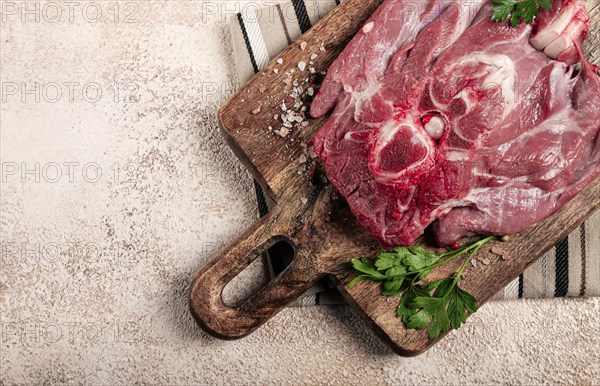 Raw steak, veal neck on the bone, fresh meat, on a cutting board, with spices, top view, without