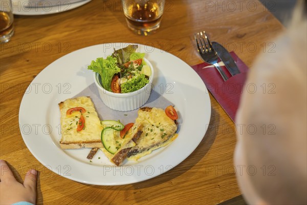 Toast with cheese and salad garnish, a child reaches for the plate, autumn creations, Cafe Kuh,