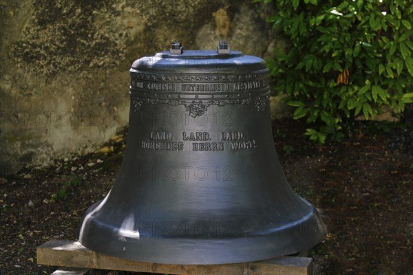 Church bell in the garden of St John's Church, inscription Land, Land, Land hear the Lord's word,