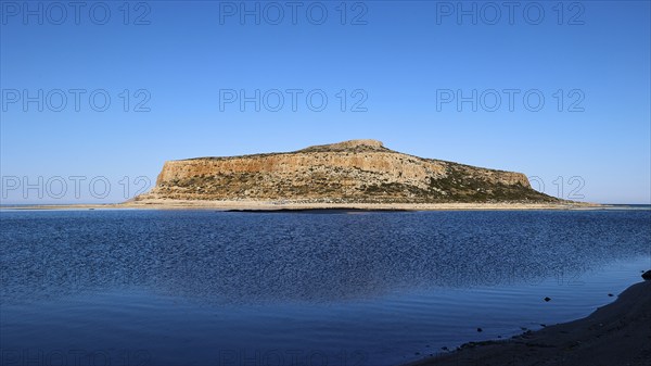 Rocky island in front of calm blue sea under clear sky, peaceful scene, Gramvoussa, Gramvoussa