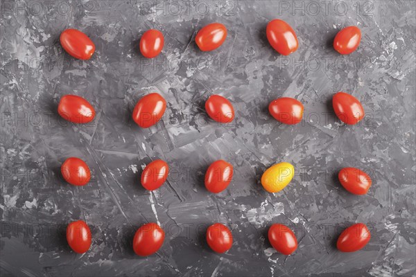 Rows of cherry tomatoes and one kumquat on a black concrete background, top view, flat lay.