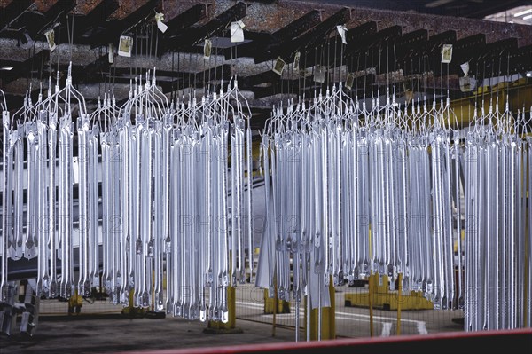 Finished galvanised steel parts lie in the factory hall of a surface finishing factory of the