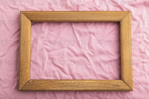 Wooden frame on pink cotton tissue. Top view, flat lay, natural textile background and texture