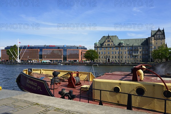 On a sunny day a boat is moored on the river in front of a city scenery with buildings, customs