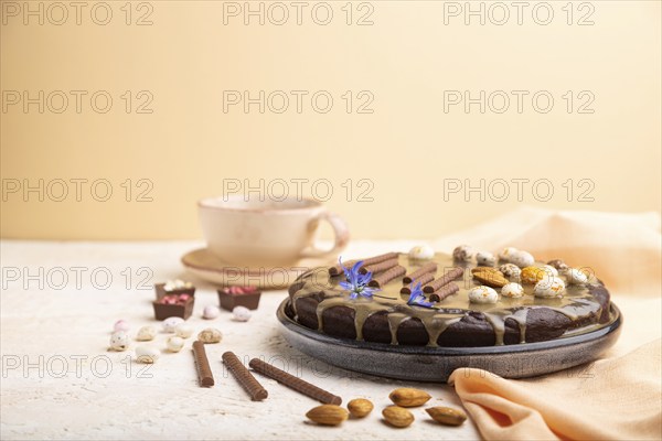 Homemade chocolate brownie cake with caramel cream and almonds with cup of coffee on a white and