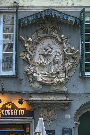 Relief group of saints and angel sculptures under a canopy on a residential building in the