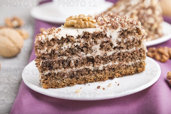 Homemade cake with milk cream and walnuts with cup of coffee on a gray concrete background and