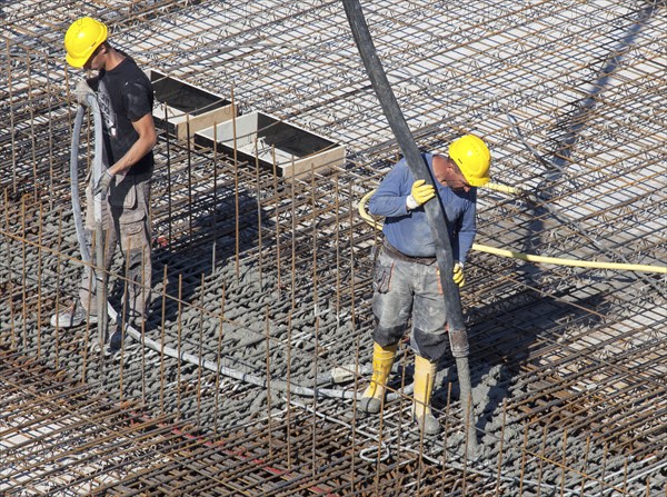 Construction workers backfilling concrete on a building site, Berlin, 19/08/2016
