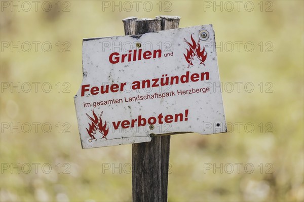 A sign with the inscription 'Barbecues and lighting fires prohibited' stands in a meadow in Berlin,