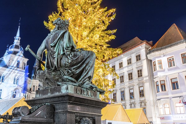 Illuminated Christmas tree, town hall, fountain with personified river goddess Drau on main square,