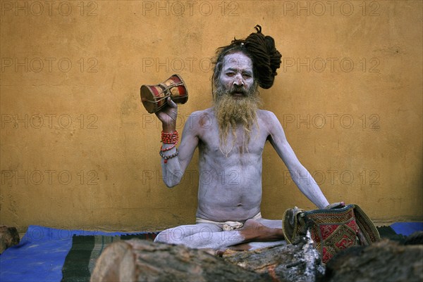 Hindu ascetic, sadhu from the naga sect, Nepal. His body is covered with ashes, he is playing