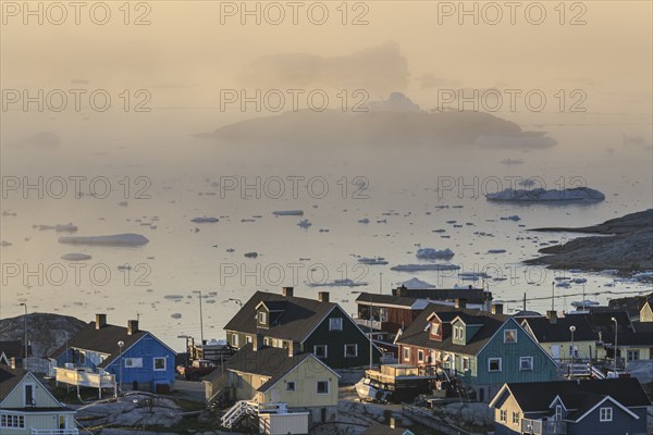 Houses in the fog in front of icebergs and ice floes, summer, midnight sun, Jakobshavn glacier and
