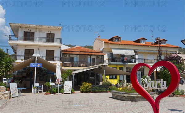 A lively town square with buildings and a large red heart in the centre, Sarti, Sithonia,